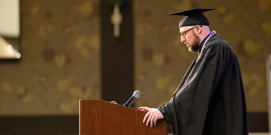 Graduate, Preston Quick, speaking at podium in black cap and gown