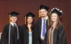 Portrait of 4 nursing students at graduation in their caps and gowns.