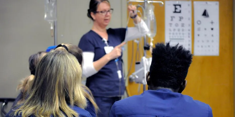 Female nurse instructing students about setting up an intravenous system