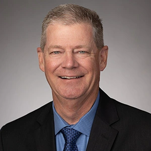 Portrait of Brian Vogelsmeier wearing a dark blazer and dark blue shirt and tie