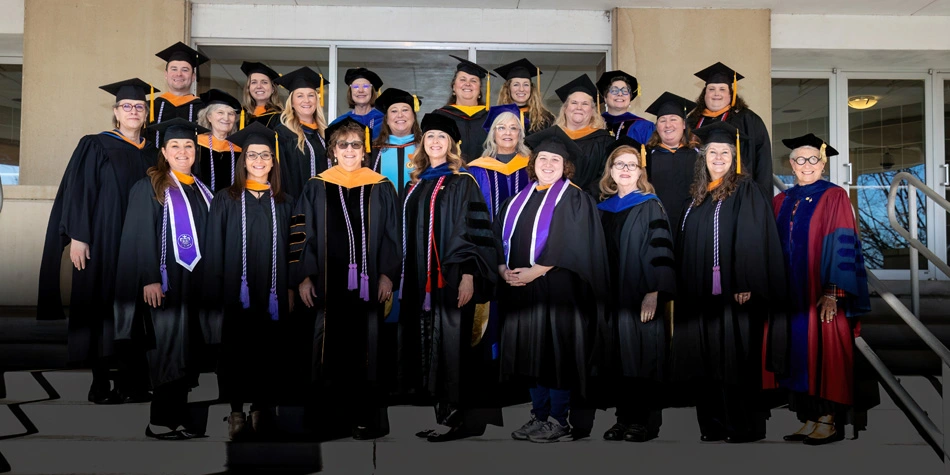 Faculty members who are certified nurses standing in three rows on steps