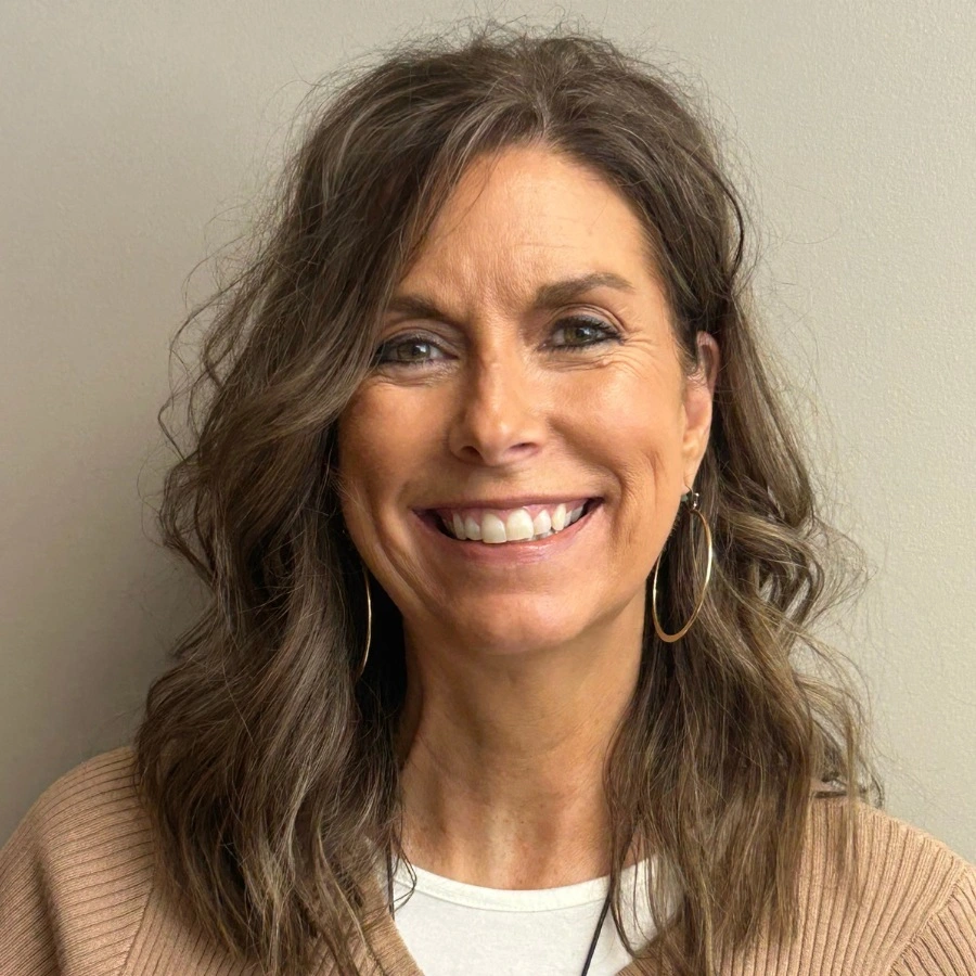 Portrait of Marcy Stackman wearing a tan sweater over a white shirt.