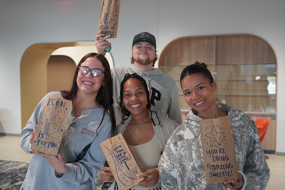 Portrait of happy students holding popcorn bags at an event.