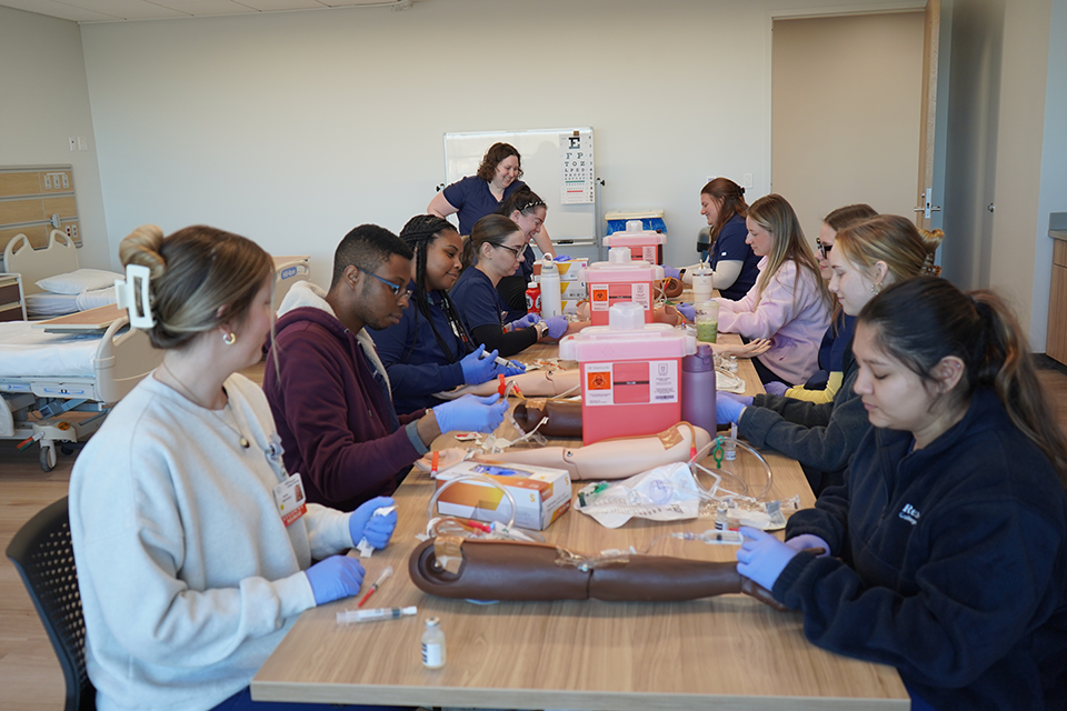 Students in the classroom learning to draw blood from the professor.