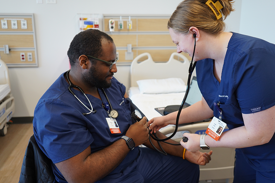 A student taking another students blood pressure in the simulation suite.