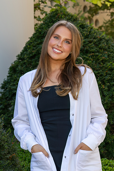 Portrait of female student wearing her white coat at graduation.
