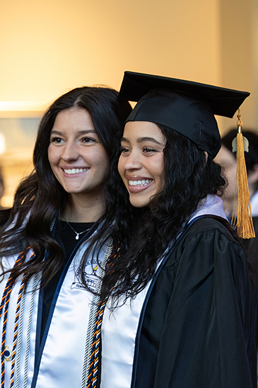 Two graduates getting their photo taken in their caps and gowns.
