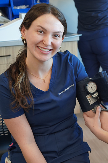 Student getting her blood pressure taken by another student in a sim lab.