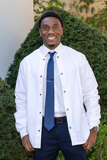 Portrait of a male student wearing his white coat at graduation.