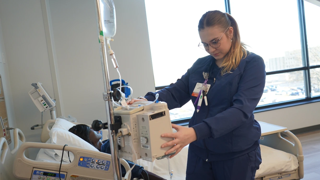 Student learning to use the IV fluid equipment in a sim lab.