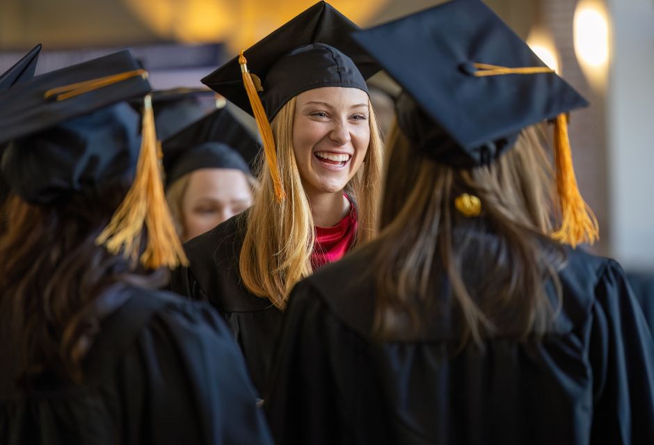 Candid of student Paxton with red hair wearing black graduation regalia and smiling.